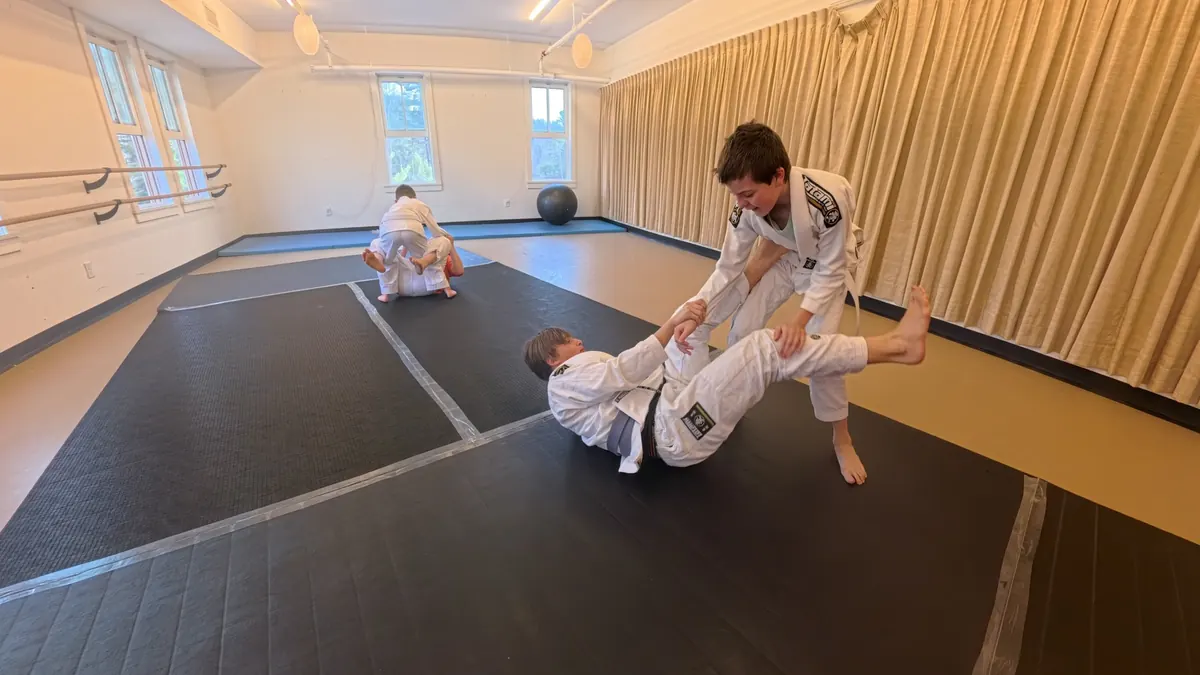 Coach calmly supervising a child on the mats during Brazilian Jiu Jitsu training in Tannersville NY
