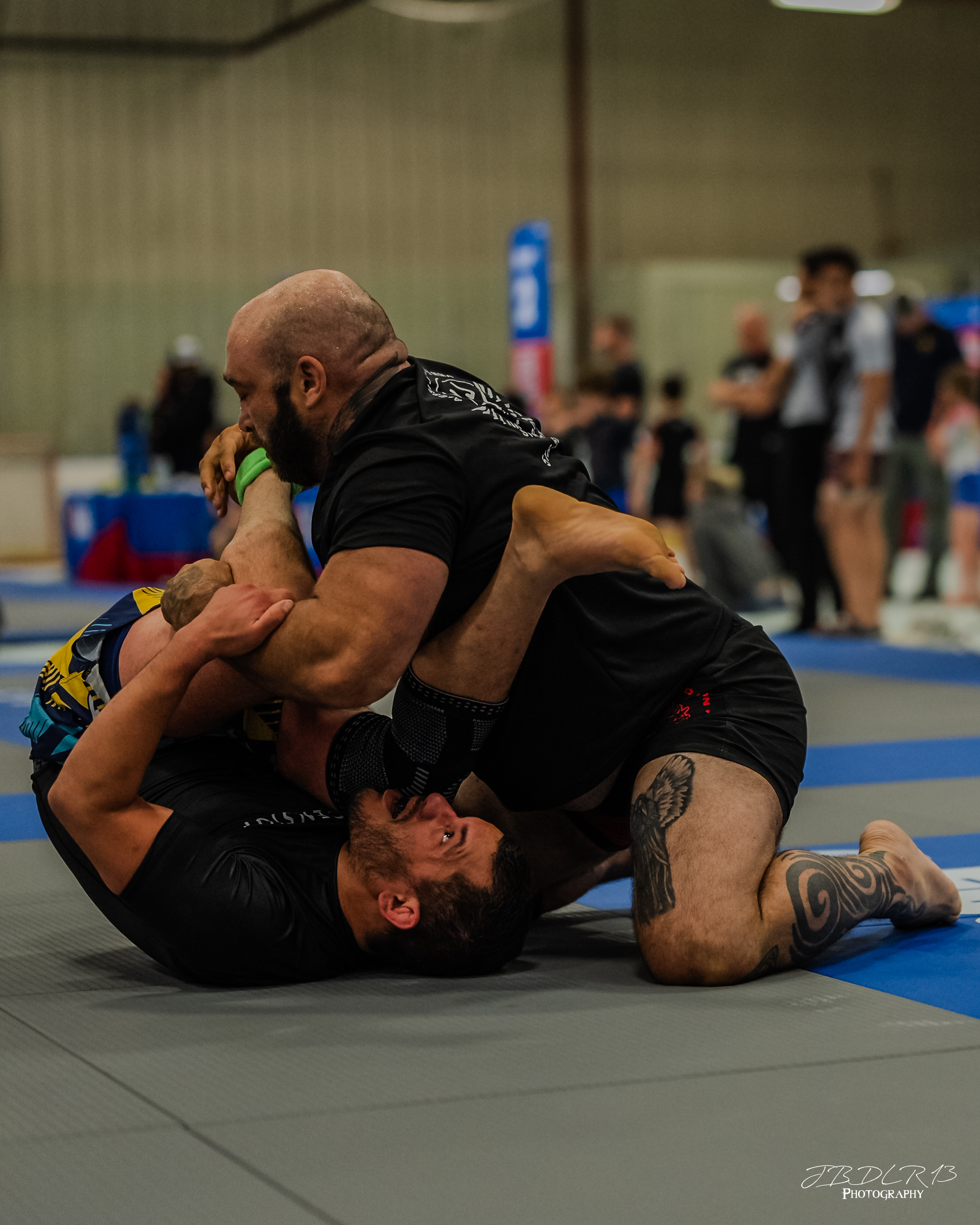 Two people practicing a BJJ move on the mats